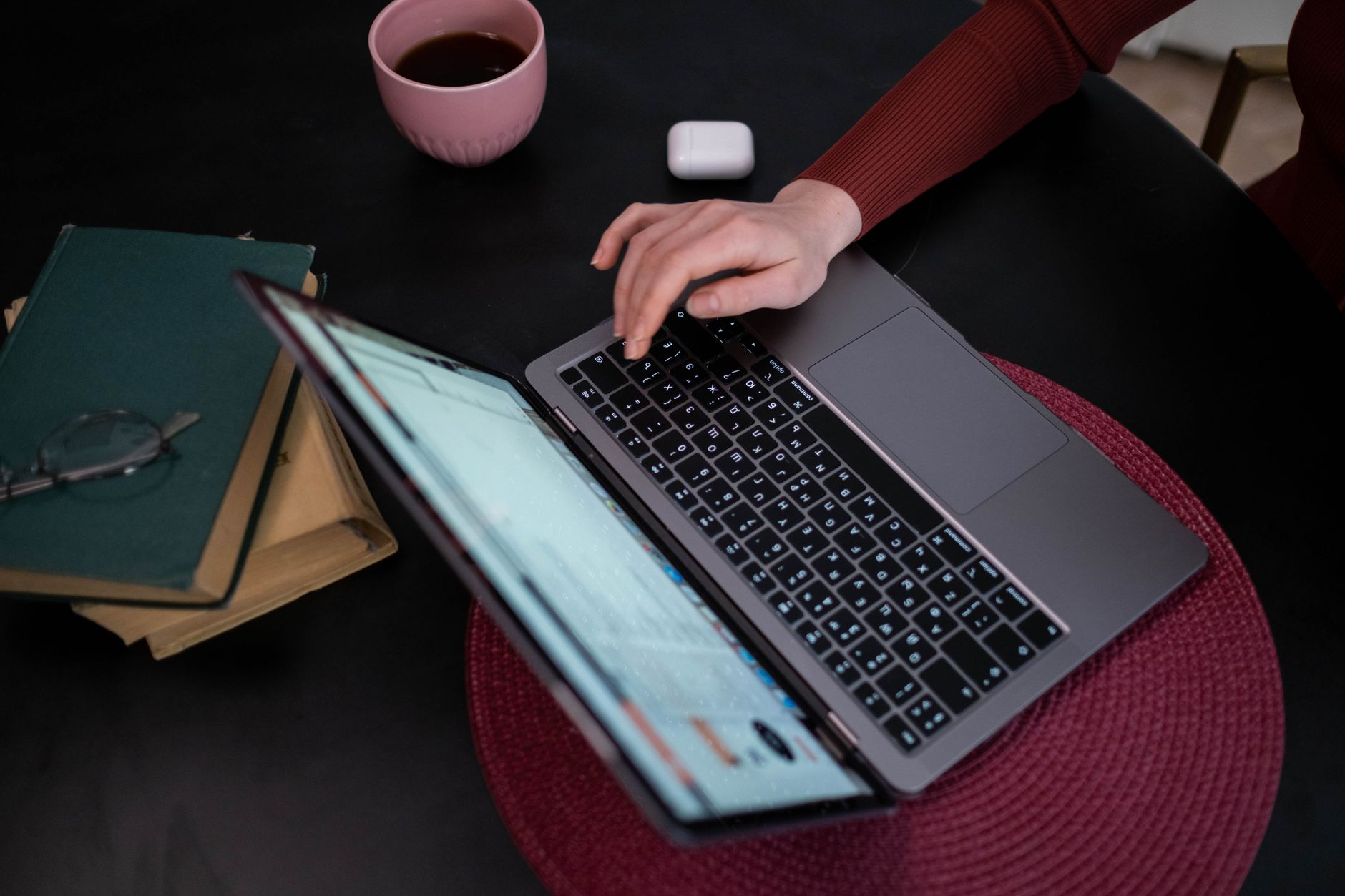Hands typing on a laptop beside a coffee