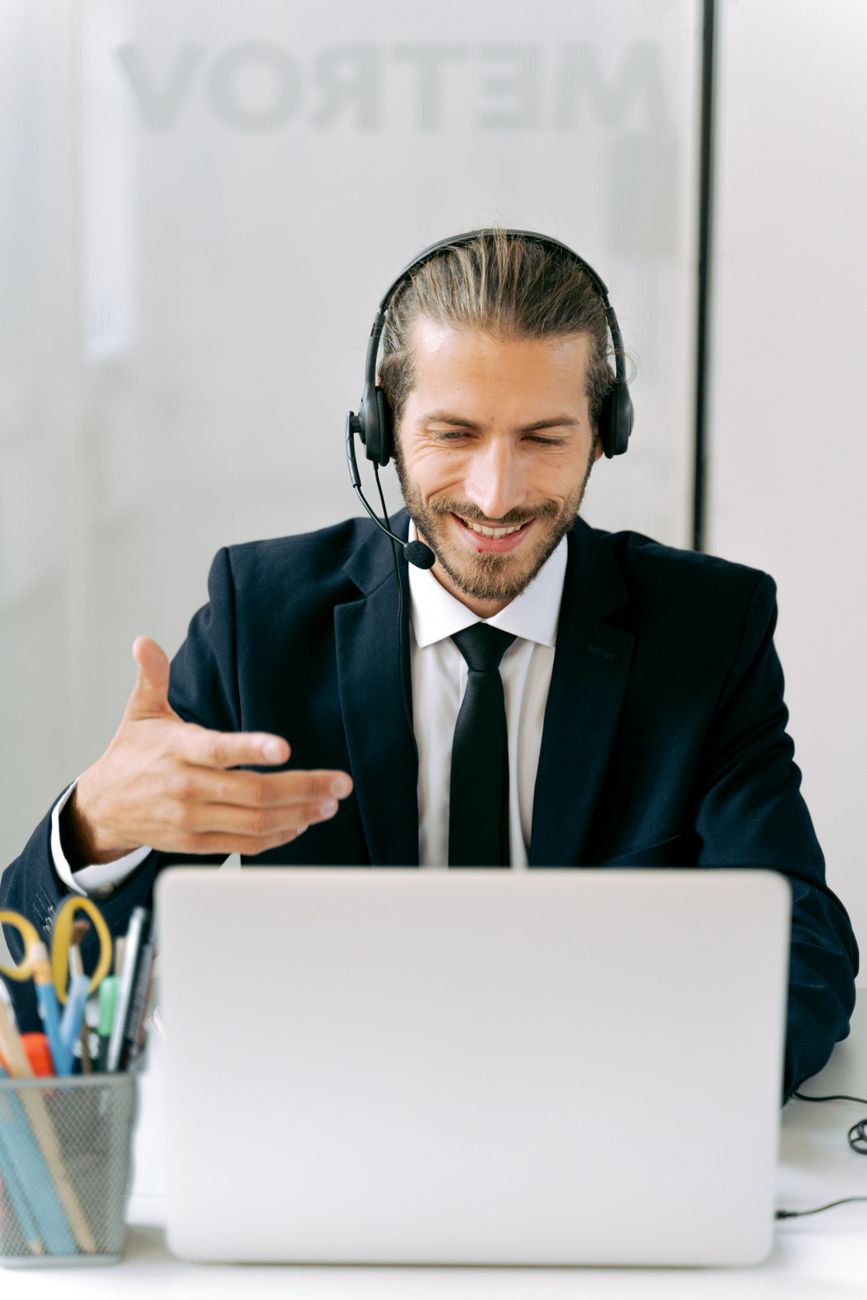 A man wearing a headset smiles during a video call