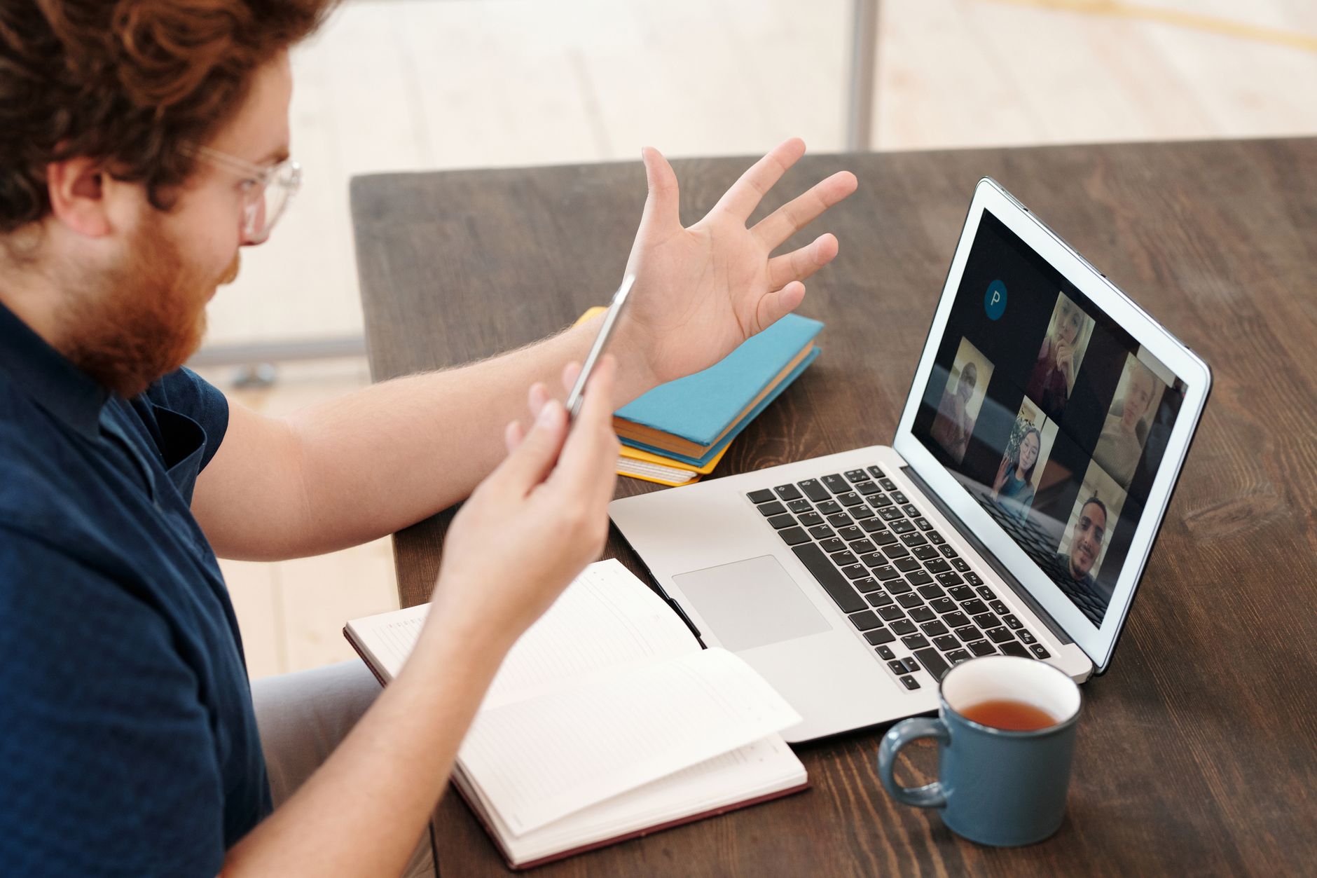 A man gestures during a video call with several participants
